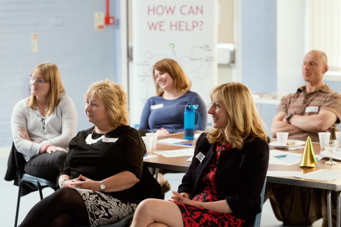 A group of educators watching a presentation at an information event