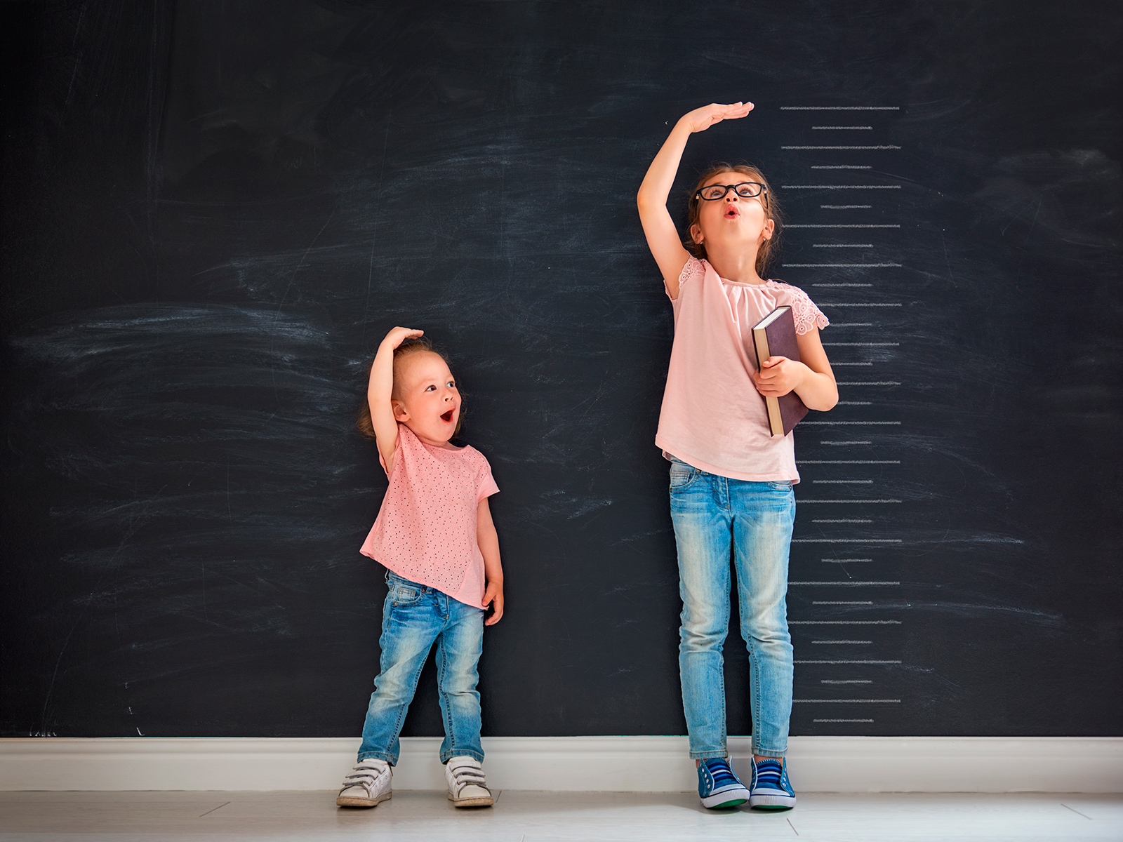 Little Girls checking their heights against a wall