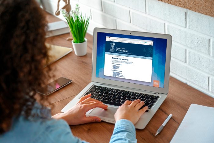 Woman with curly hair using the new Lanarkshire Firm Base website on a laptop