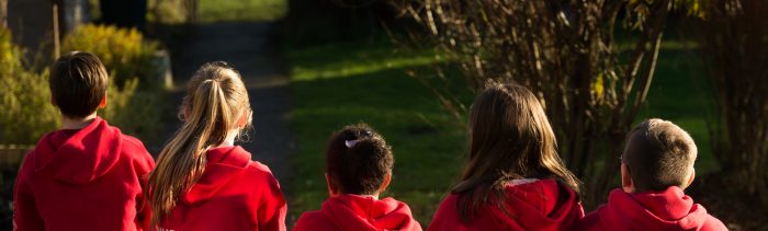 Children in red hoodies looking off in to the distance away from camera