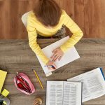 Looking down at a young girl at her desk writing in her notebook