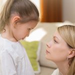 Mother kneeling to talk to pre-teen daughter about a serious subject