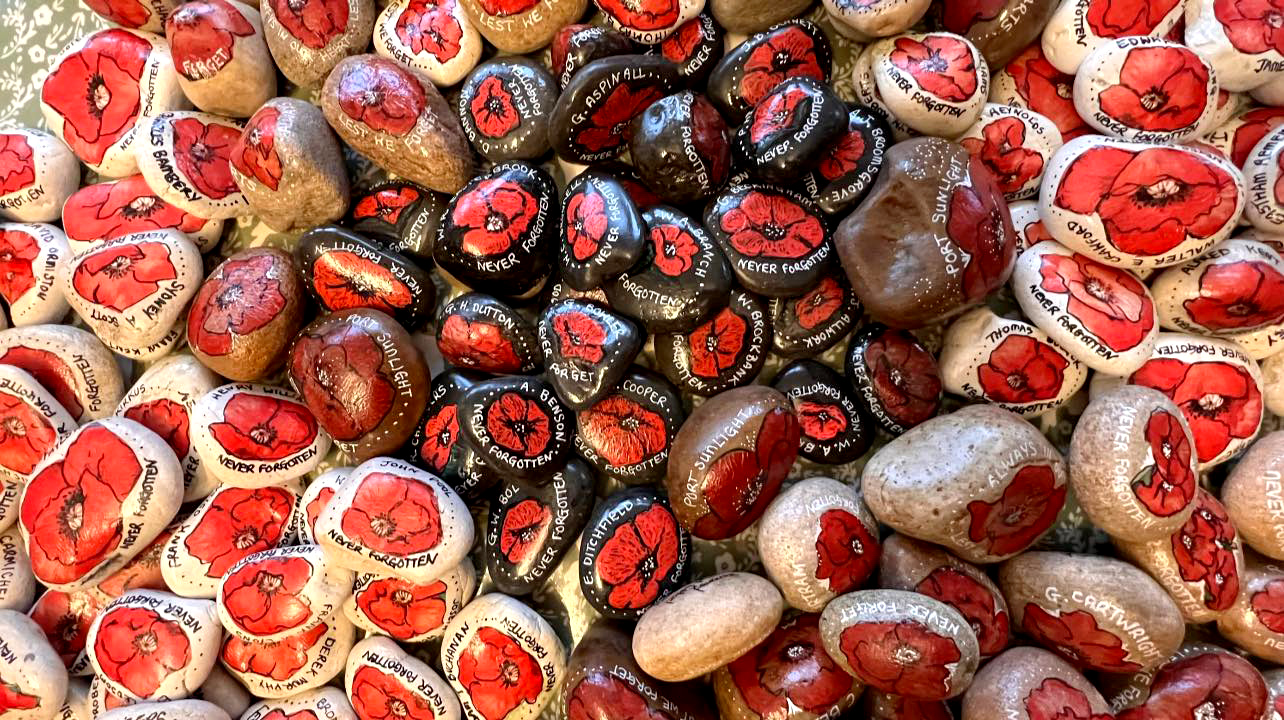 A collection of pebbles painted with remembrance messages and poppies