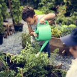 Two children tend plants in raised beds at a comunity garden.