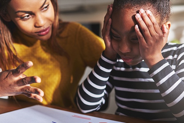 A teacher sits with a struggling pupil working on maths problems.