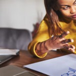 A teacher sits with a struggling pupil working on maths problems.