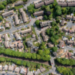 An aerial view of a large housing estate surrounded by trees, a railway and trunk roads.