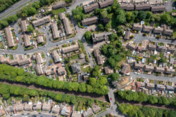 An aerial view of a large housing estate surrounded by trees, a railway and trunk roads.