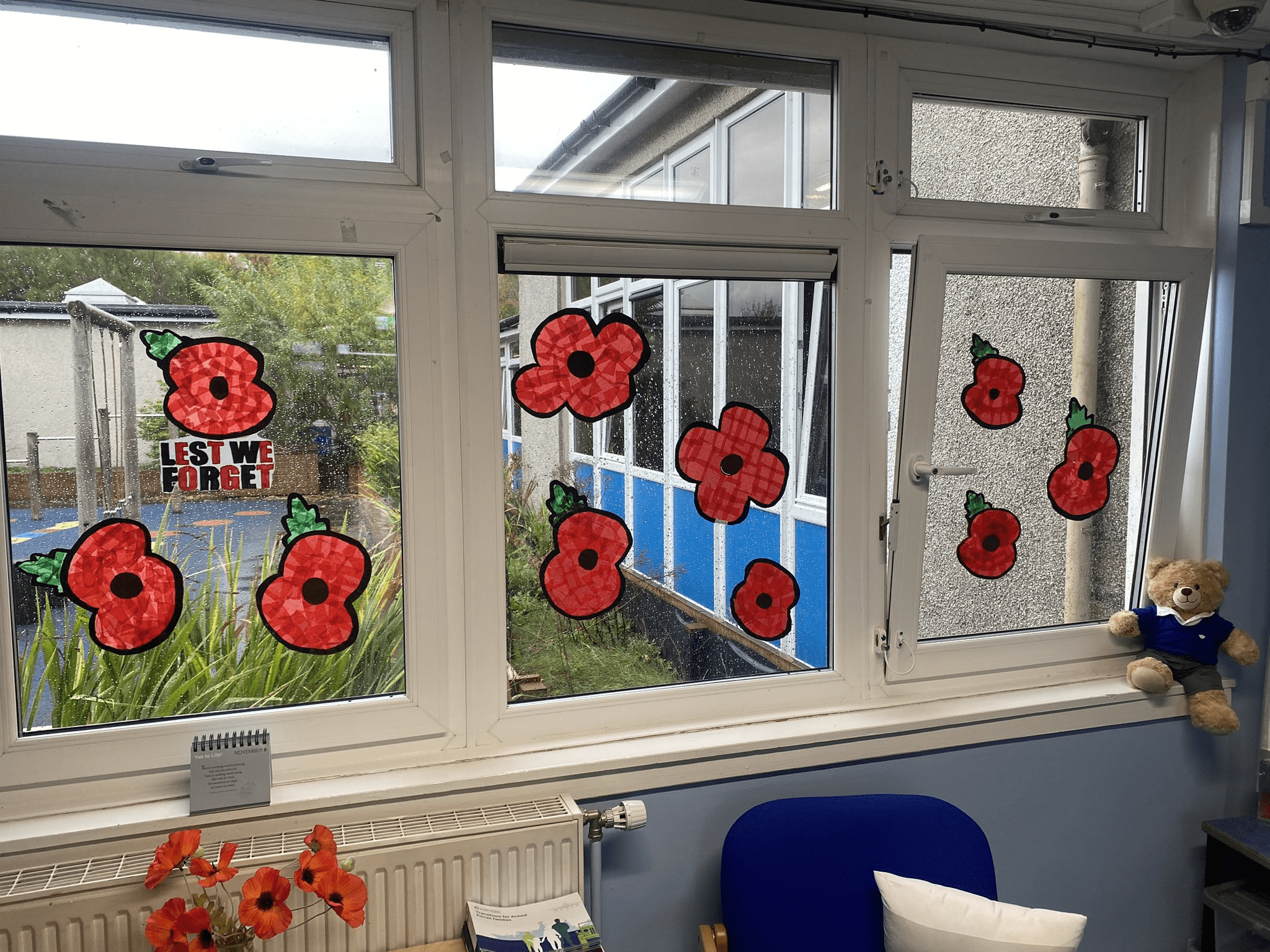 A number of hand drawn poppies are displayed on one of the school windows